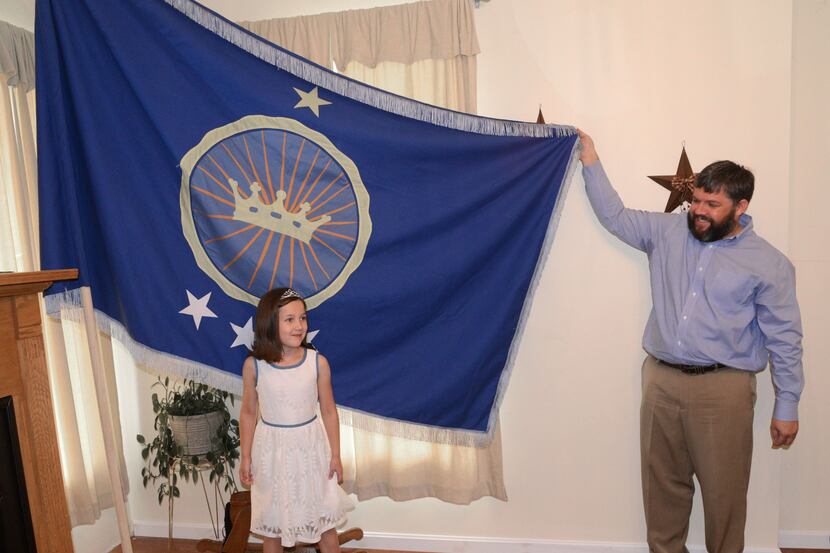 Jeremiah Heaton and his seven year-old daughter, Emily, show the flag their family designed.