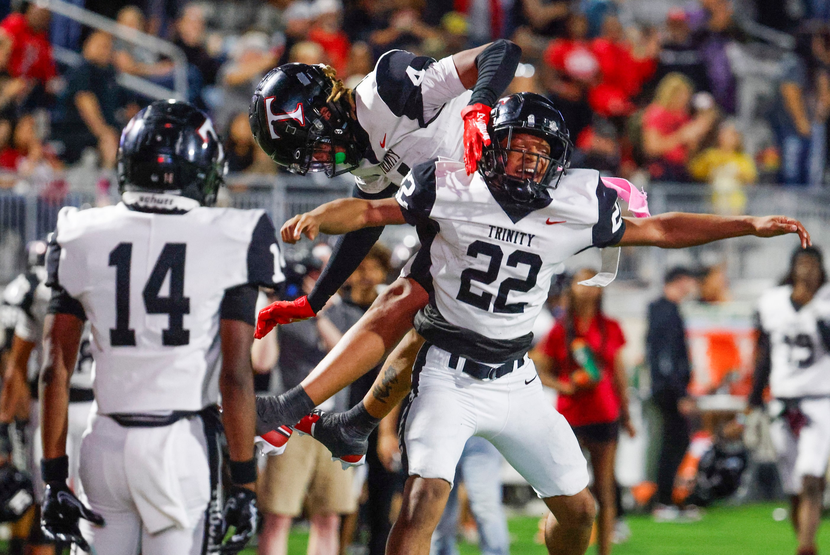 Trinity High’s JT Harris (22) and Jarvis Heimuli (back) celebrate a touchdown by Harris...