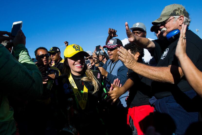 Top Fuel winner Brittany Force, center, gets high-fives from fans on her way to receive her...