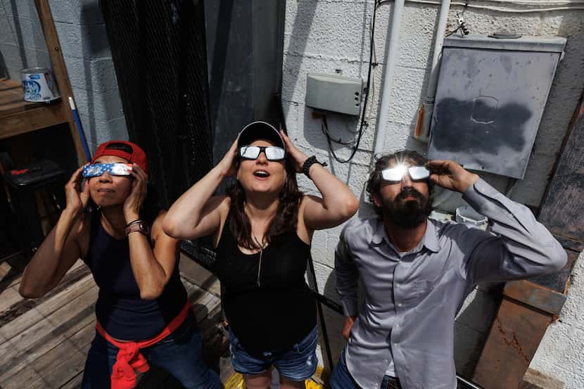 Liz Gutierrez, (from left) Melissa Ford and Jonathan Dengle look at the total eclipse at The...
