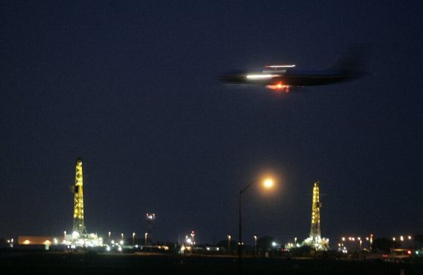 Incoming American Airlines jet with natural gas wells in the background at dusk at DFW...