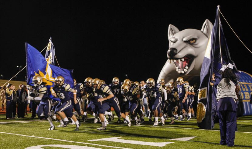 The Little Elm Lobos run out on the field at the start of the football game between Frisco...