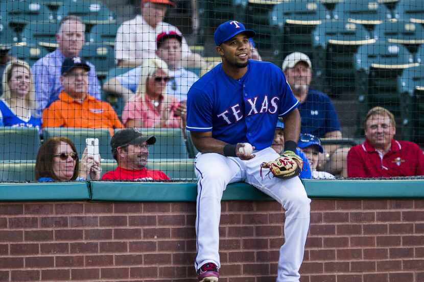 Texas Rangers fans on the front row get a thrill as shortstop Elvis Andrus (1) takes a seat...