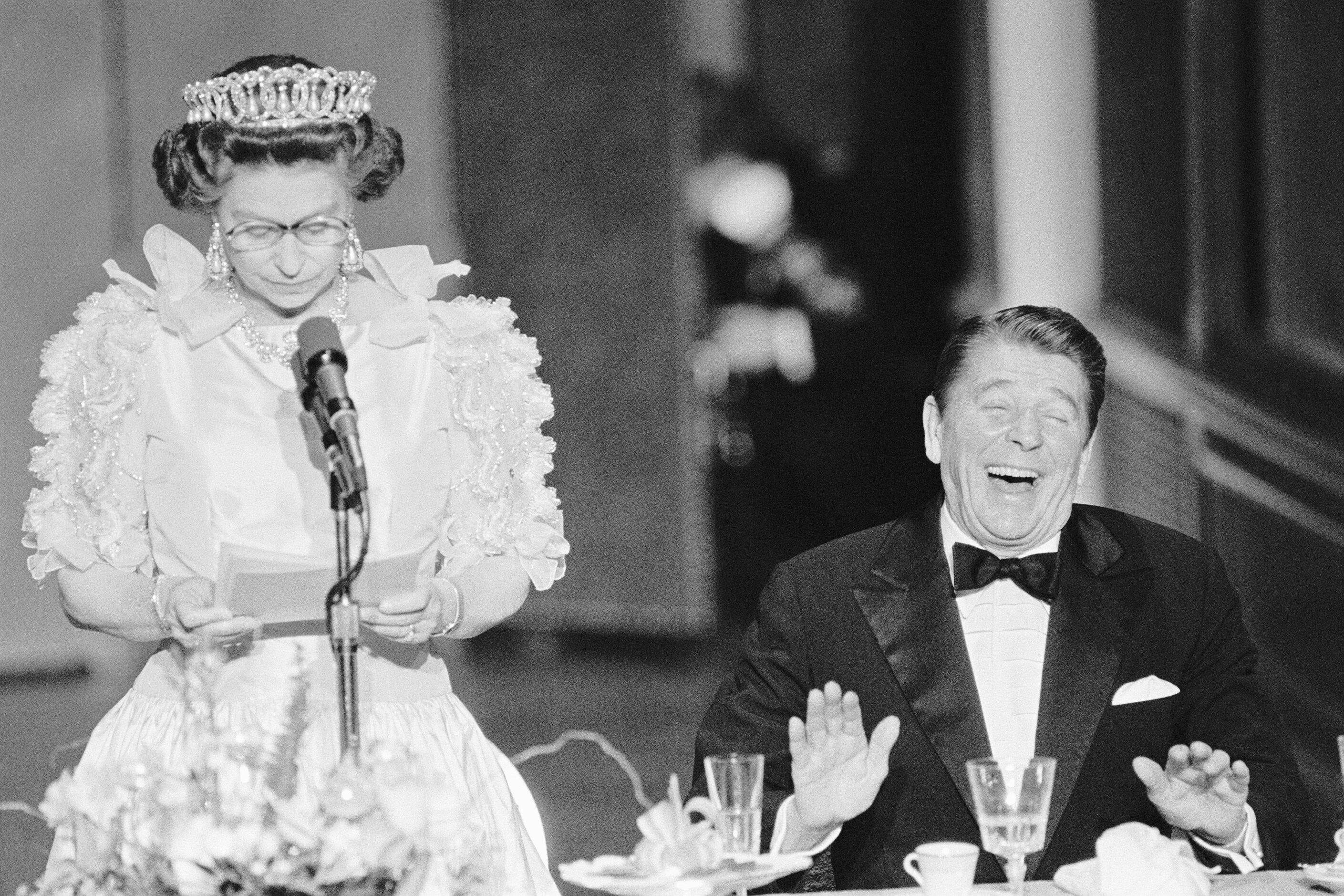 President Reagan laughs following a joke by Queen Elizabeth II, who commented on the lousy...