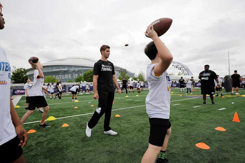 NFL Draft prospect UCLA quarterback Josh Rosen, center, helps instruct participants during a...