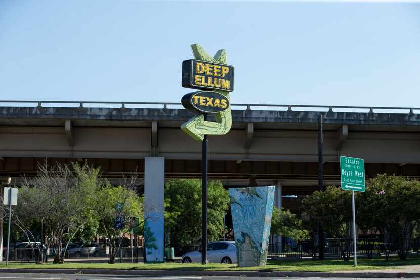 The Deep Ellum, Texas, sign on the corner of Main Street and Good-Latimer Expressway points...