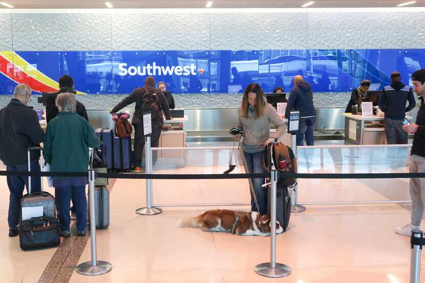 Travelers wait in line to speak with Southwest Airlines agents at the airline’s ticket...