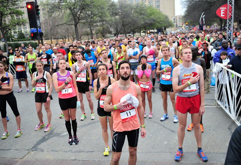 Runners listen as the national anthem is played before the start of the Dallas Rock N' Roll...