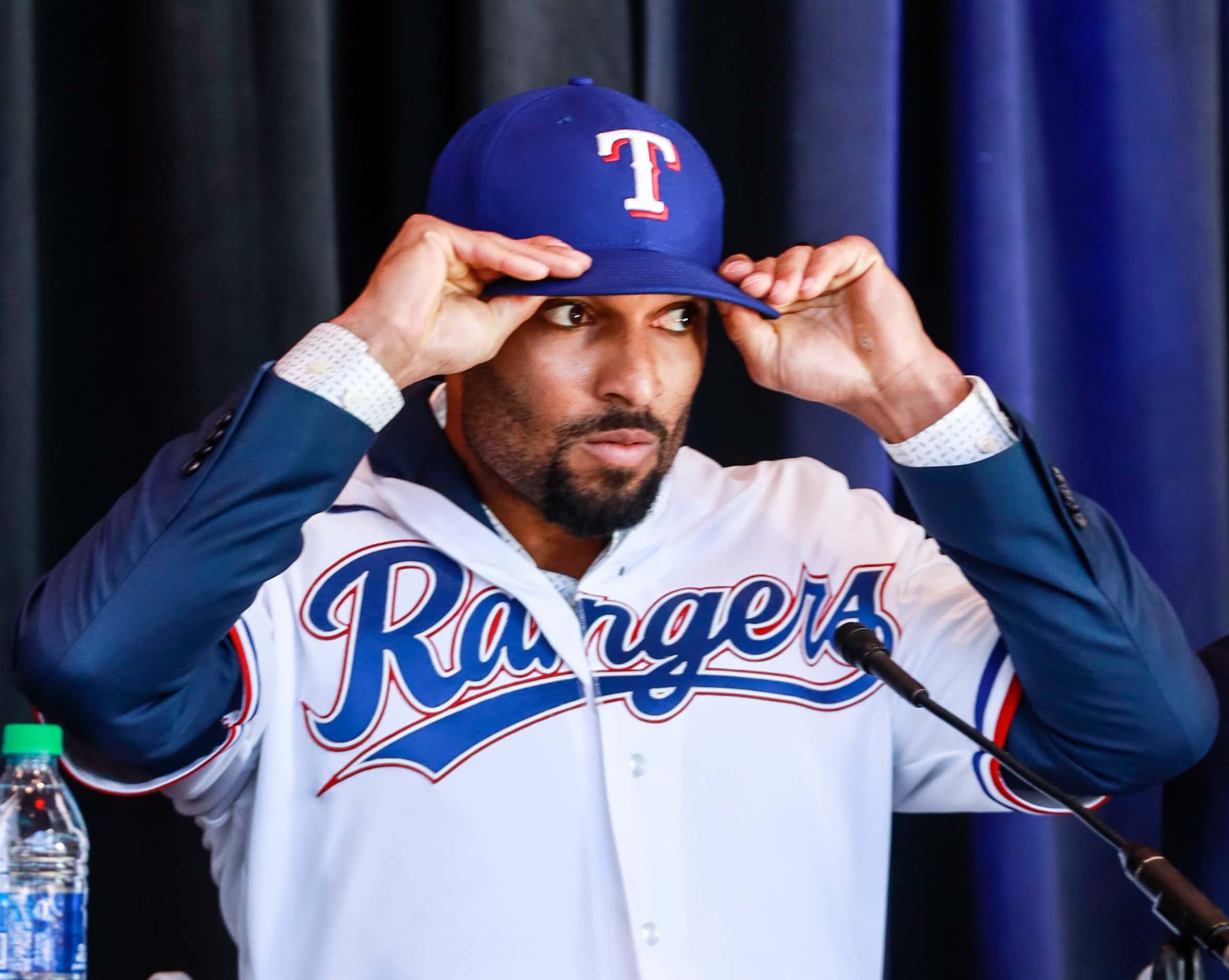 Marcus Semien adjusts his Texas Rangers baseball hat at a news conference at Globe Life Park...