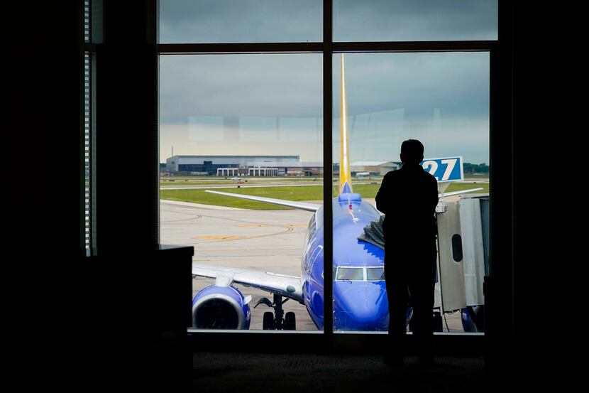 A man looks out over a Southwest Airlines 737 parked at a gate at Houston Hobby Airport.