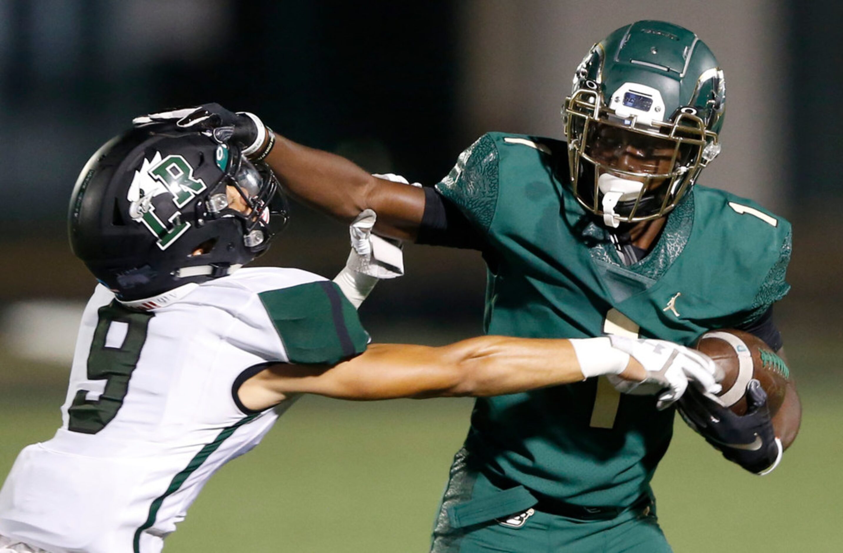 DeSoto's Jordan Brown (1) stiff arms Mansfield Lake Ridge's Omari Oggs (9) during the first...