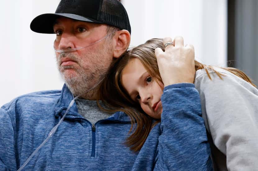 Josh Welch, 47, left, comforts his youngest daughter, Maggie, 9, while talking to his wife...