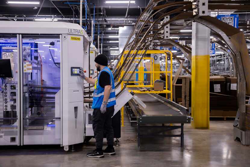 A worker controls a box making machine inside of Walmart’s 1.5-million-square-foot online...