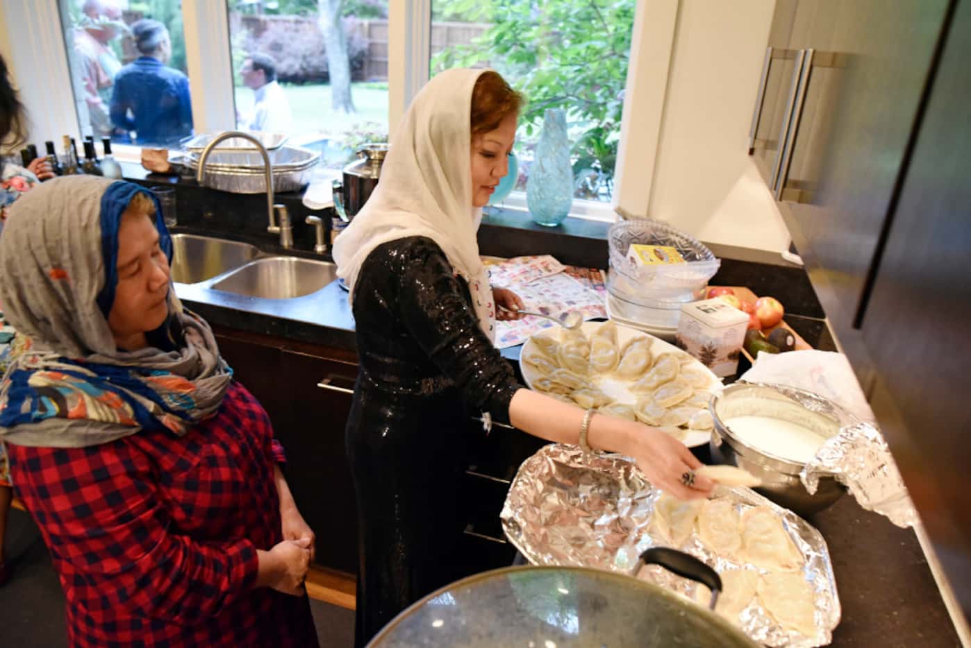 Sharifeh Hasani (left) watches her sister, Jamileh Jafari, prepare beef dumplings known as...