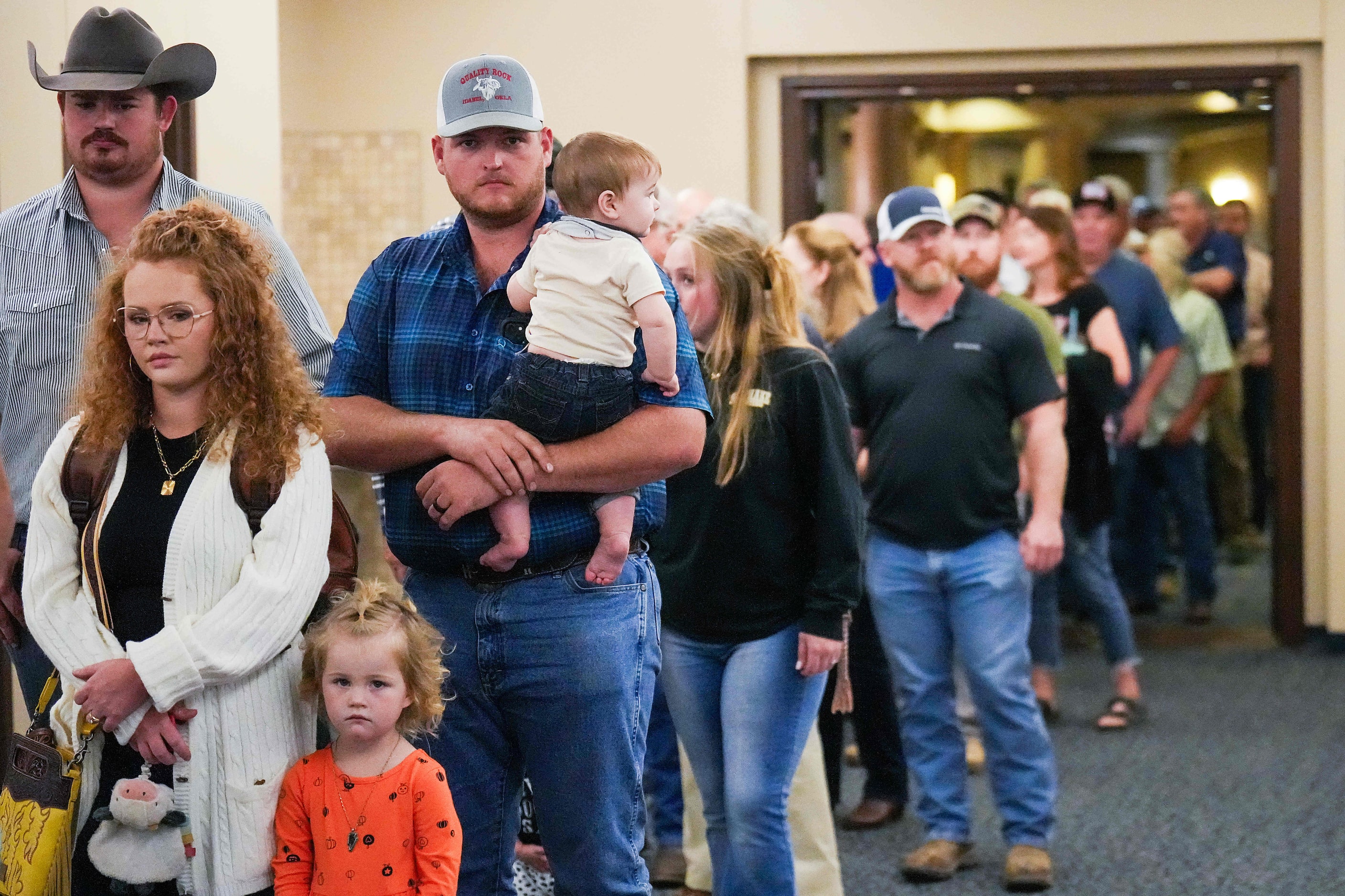 Heath Holt holds his six-month old son Robert as he waits in a long line to sign in for a...