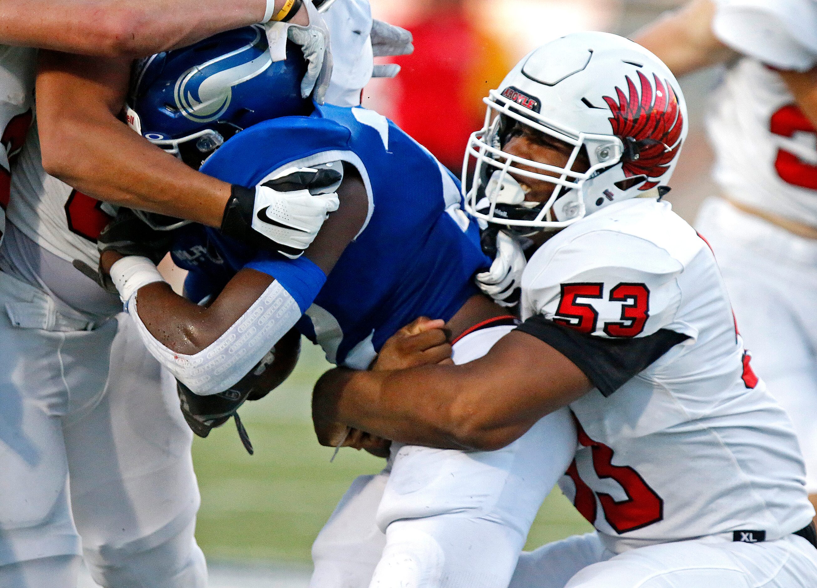 Argyle High School defensive lineman Jadon Scarlett (53) wraps up Nolan Catholic High School...