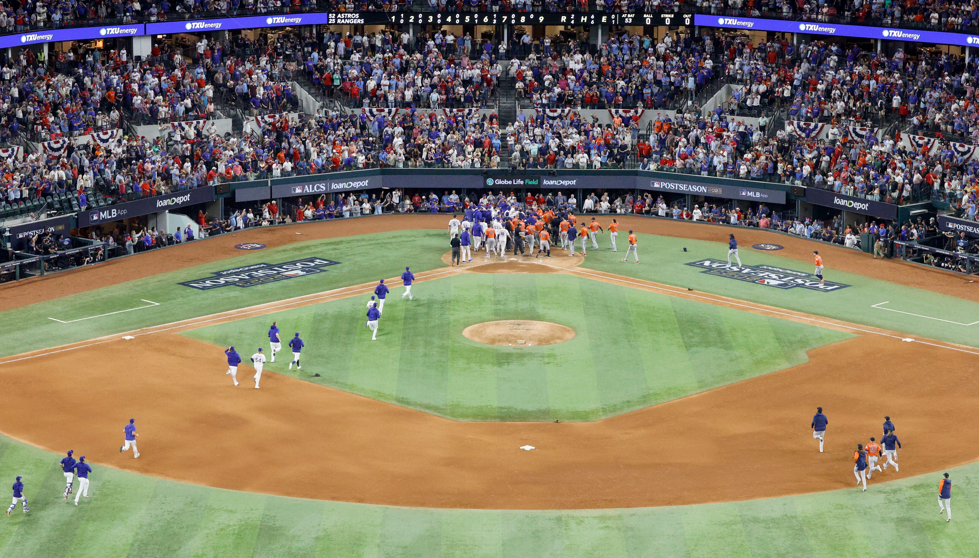 Players from the Texas Rangers and Houston Astros bullpens run towards home plate as the...