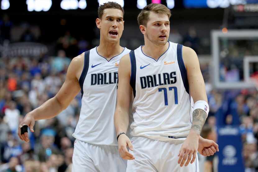 DALLAS, TEXAS - MARCH 18: Dwight Powell #7 of the Dallas Mavericks reacts with Luka Doncic...