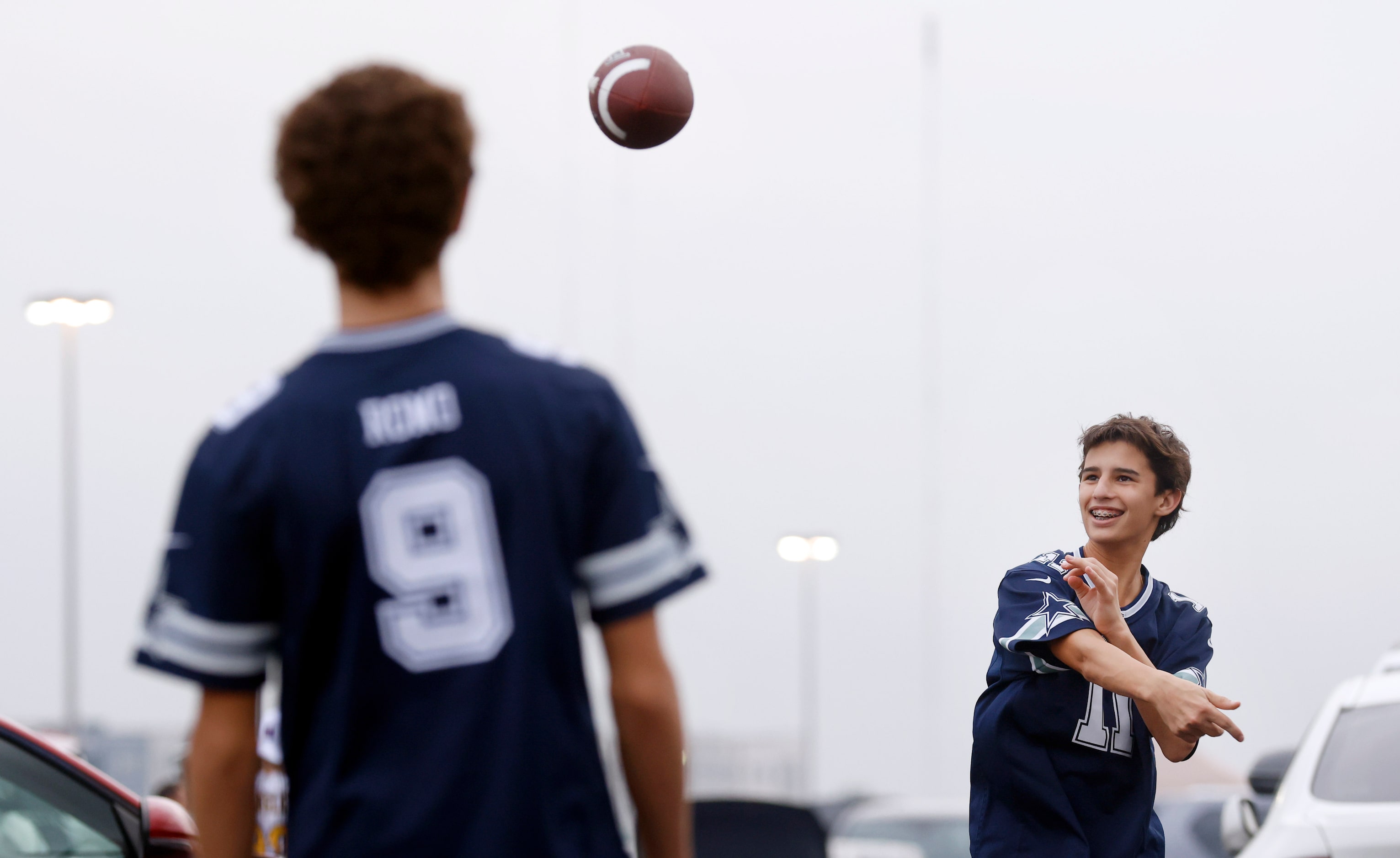 Dallas Cowboys fans Ethan Rosenthal (right) throws a pass to his friend Marco Reda in the...