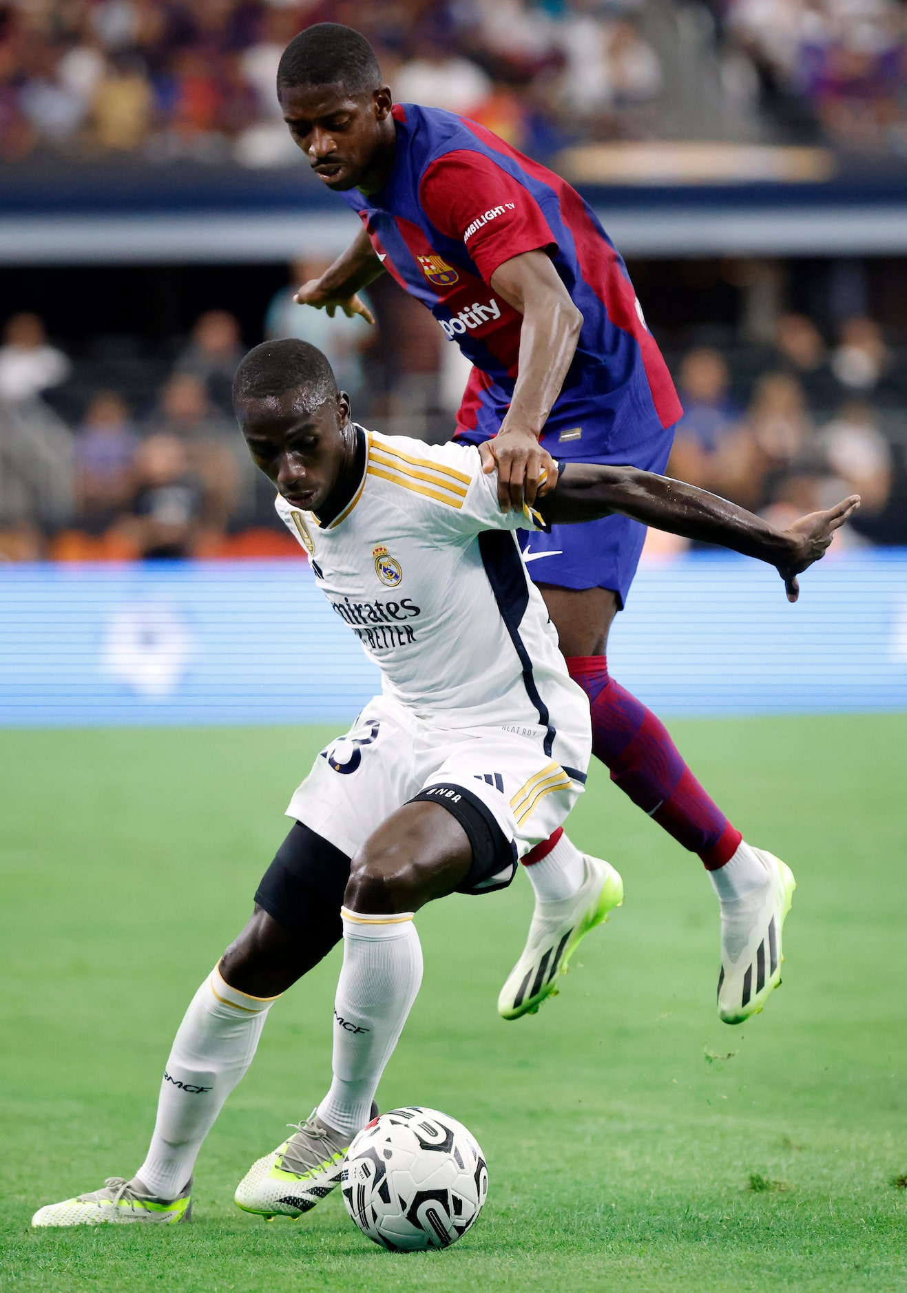 Barcelona forward Ousmane Dembélé (7) tries to take the ball back from Real Madrid defender...