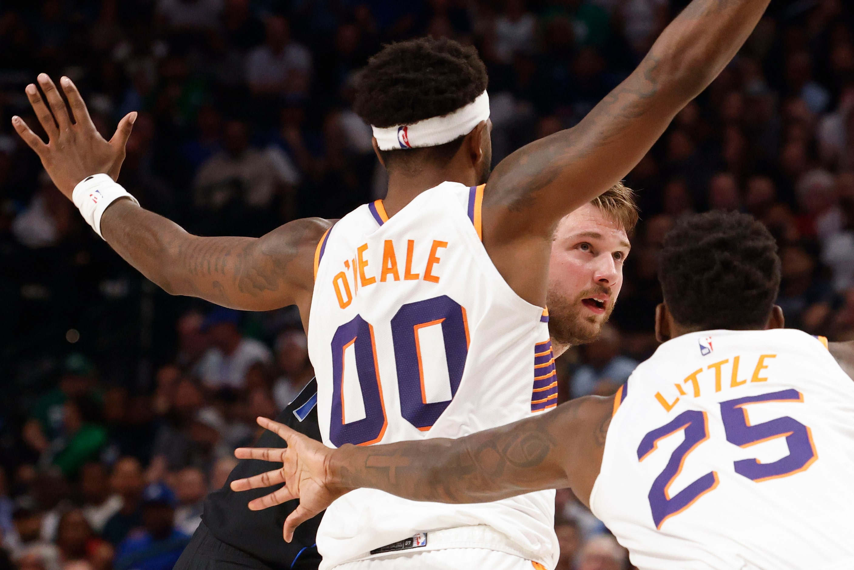 Dallas Mavericks guard Luka Doncic (center) looks to shoot past Phoenix Suns forward Royce...