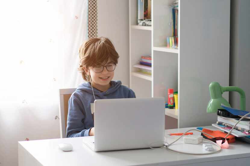 Boy sitting at a computer taking online courses in living room