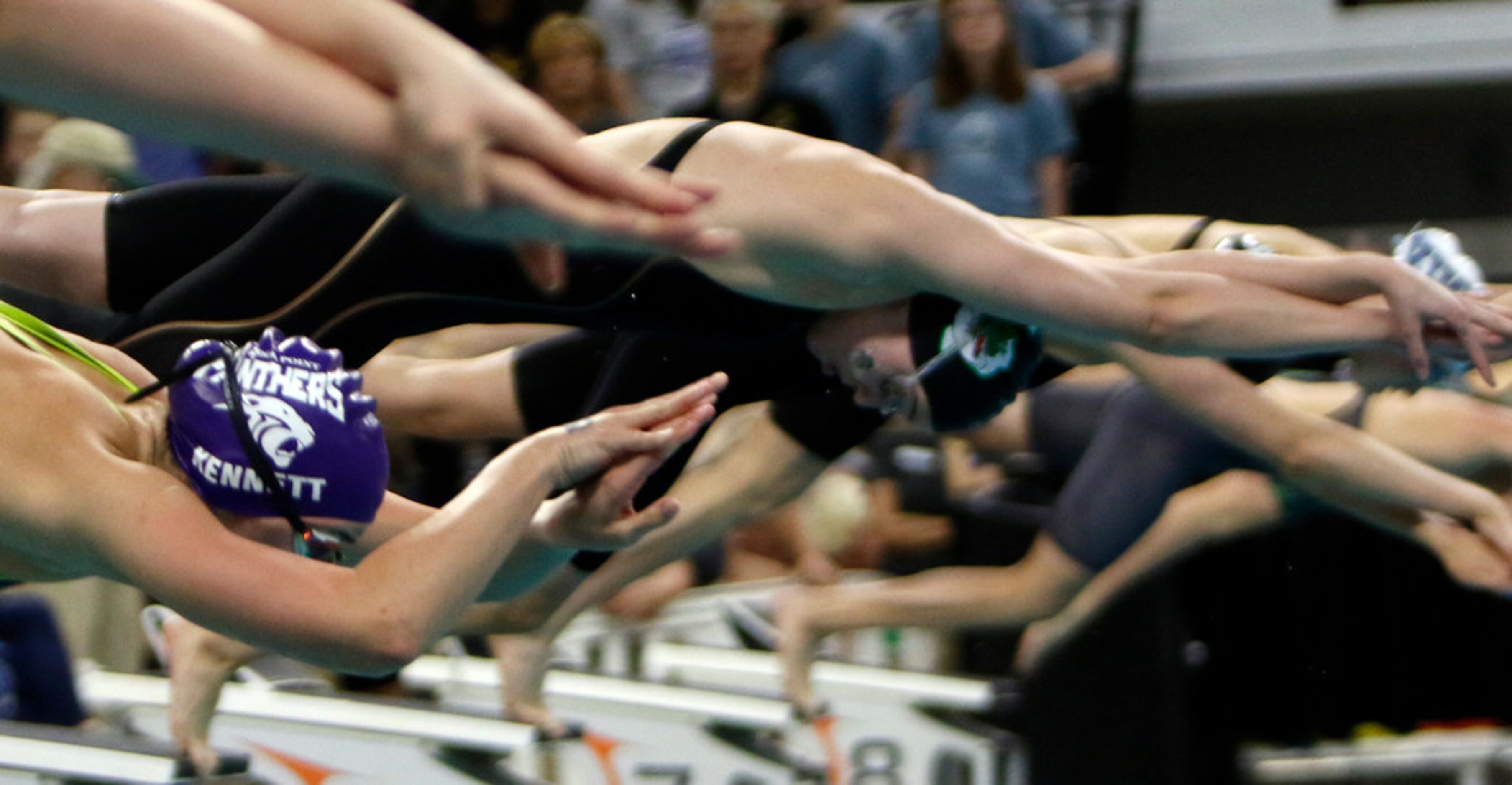 Southlake Carroll's Kit Kat Zenick, center, is framed by the arms of legs of other swimmers...