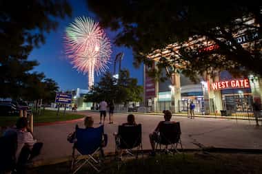 Fans relax in the parking lot and watch fireworks explode over Toyota Stadium after a 3-2...