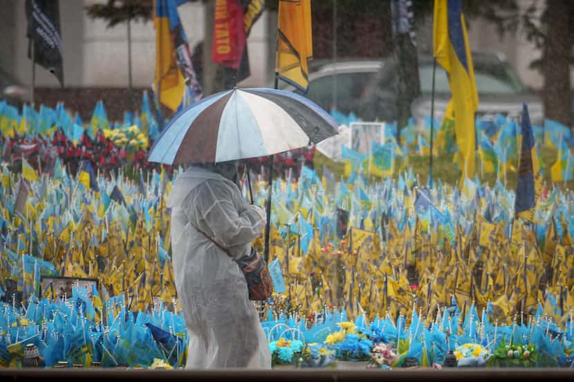 A woman walks by Ukrainian flags placed at a memorial for fallen soldiers downtown Kyiv,...