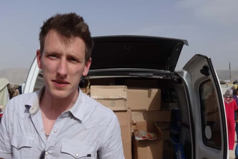 This undated photo provided byhis family shows Peter Kassig standing in front of a truck...