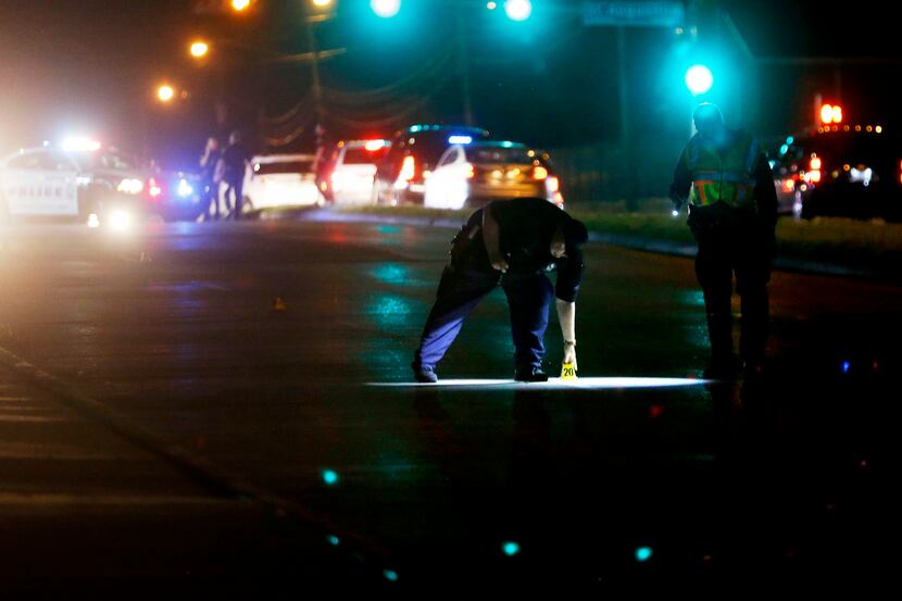 Dallas police mark evidence while investigating the scene of a shooting where a 13-year-old...