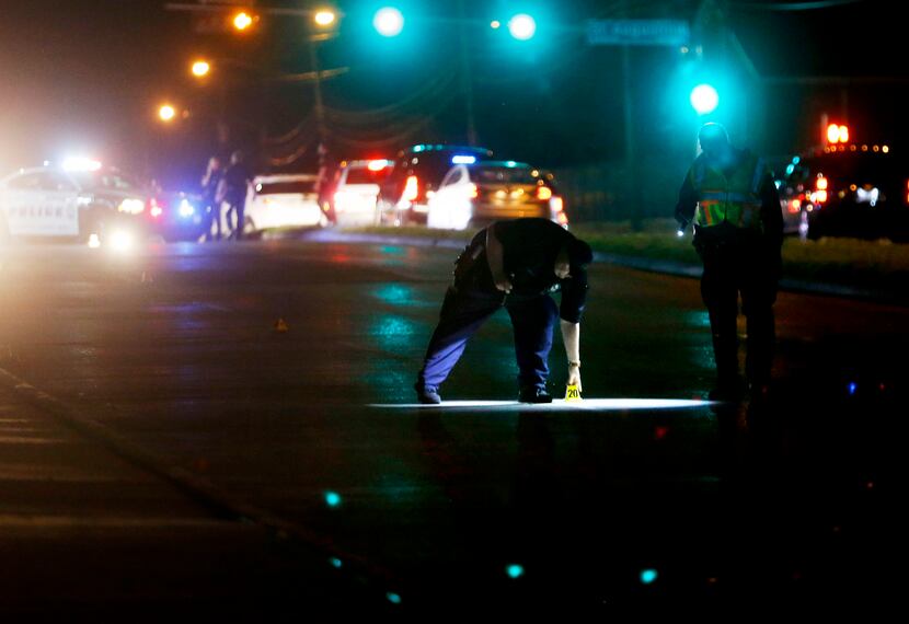 Dallas police mark evidence while investigating the scene of a shooting where a 13-year-old...