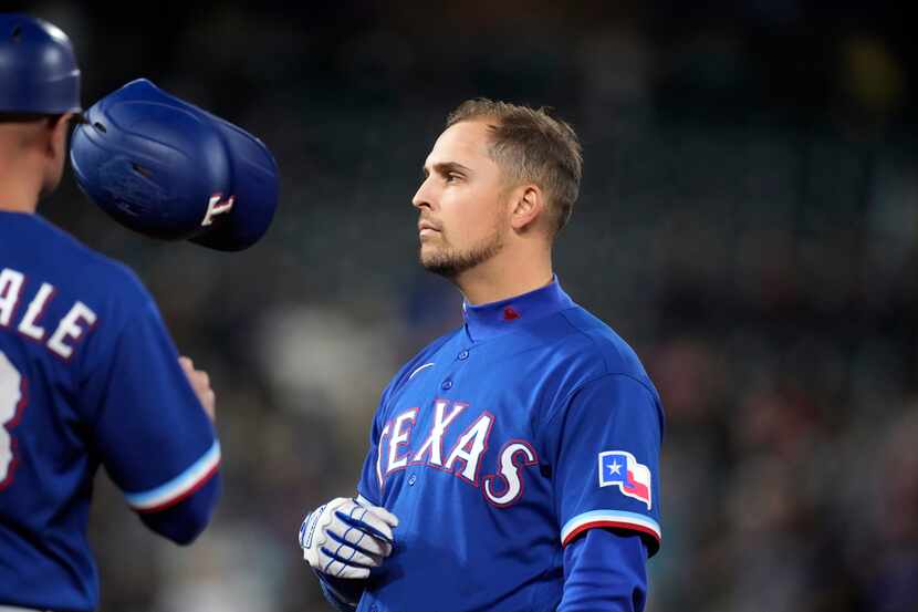 Texas Rangers' Nate Lowe, right, tosses his batting helmet to first base coach Corey...