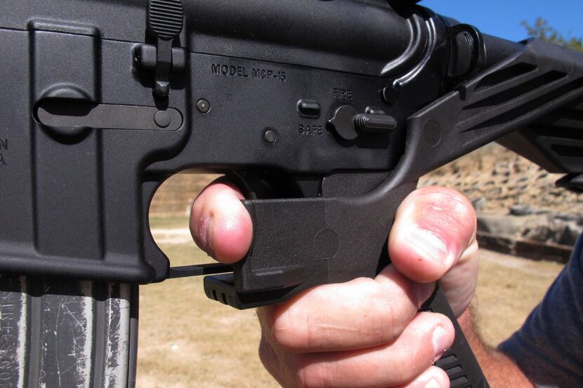 Shooting instructor Frankie McRae demonstrates the grip on an AR-15 rifle fitted with a bump...