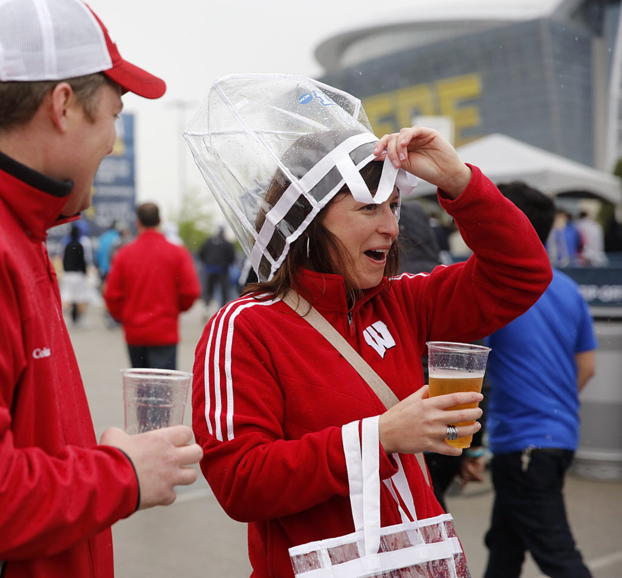 Wisconsin fan Angie Achenbach uses a clear plastic tote bag to take cover from the rain at...