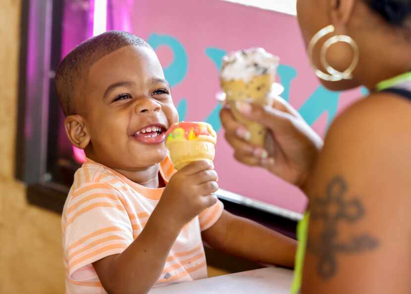 Legend Phillips, 1, laughs with Requill Phillips (right) as they eat ice cream at Henry's...