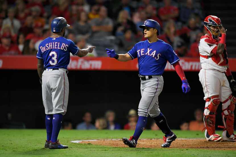 Texas Rangers' Shin-Soo Choo, center, of South Korea, is congratulated by Delino DeShields,...