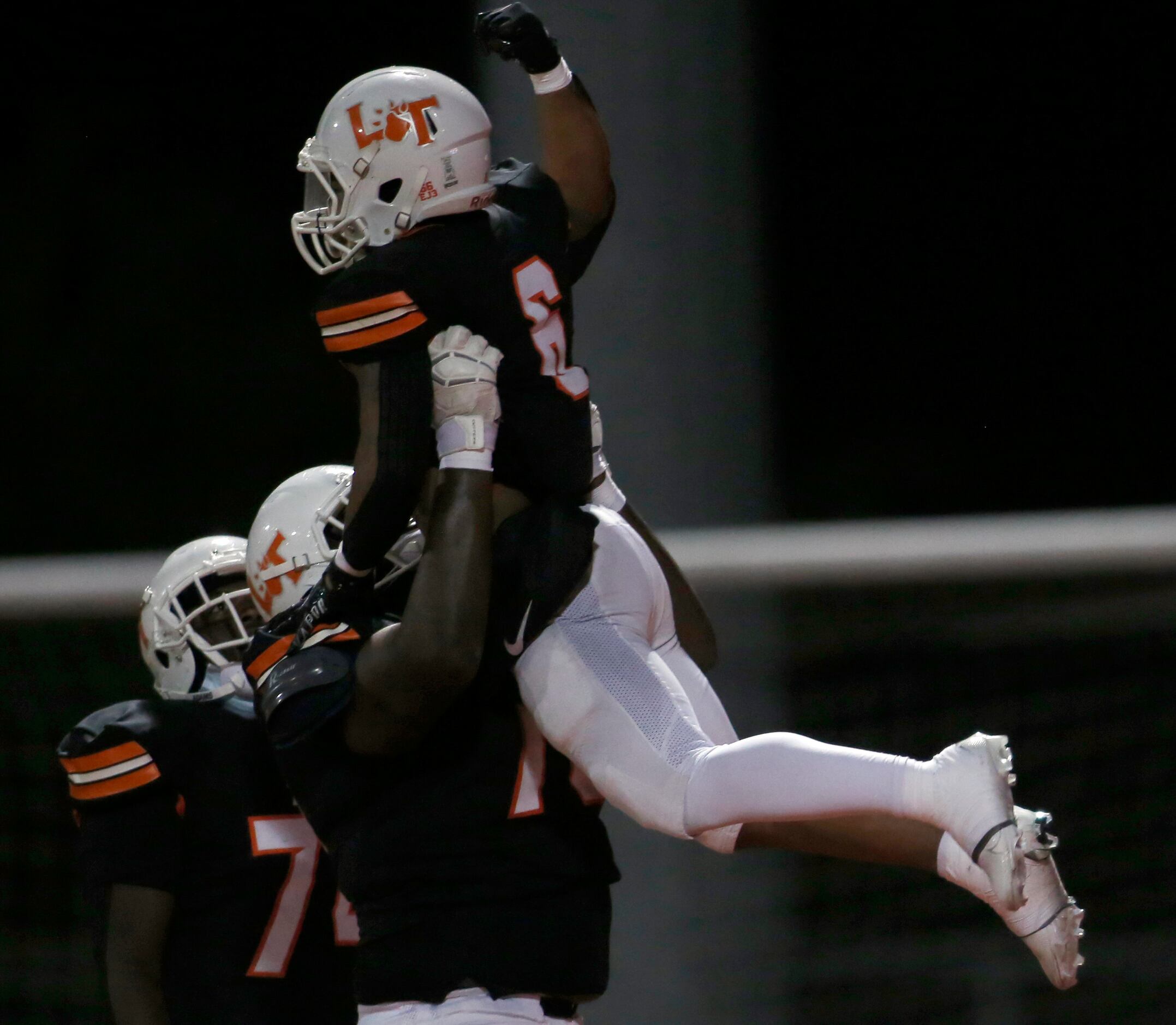 Lancaster running back DQ James (6) is lifted by offensive lineman Joseph Amos (73) as the...