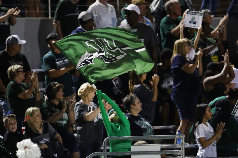 A young Waxahachie Indians fan waves the school's flag as fans show their approval following...