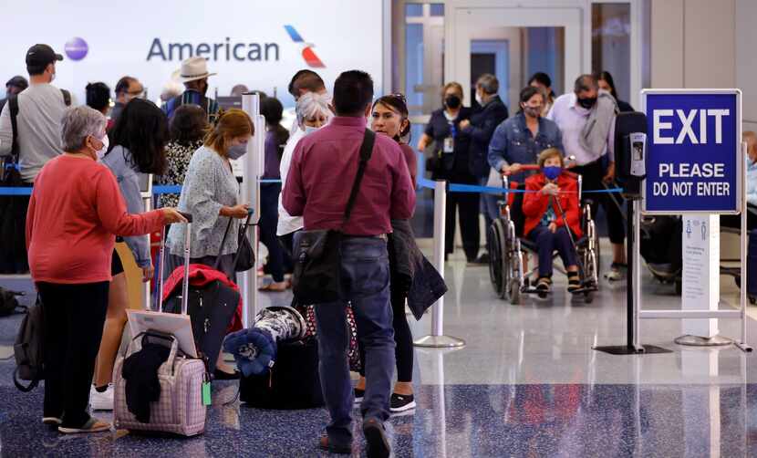 Passengers wait in line to rebook their canceled American Airlines flight in Terminal D at...