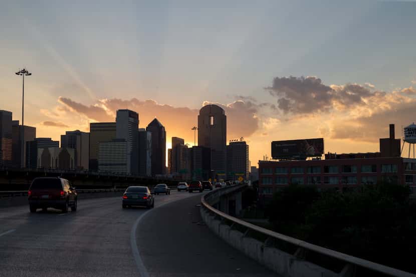 The sun sets on the Dallas skyline on the ramp from Interstate 30 west to I-345 north, an...
