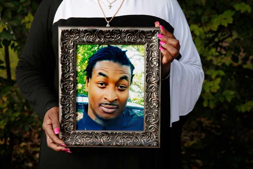 O'Shae Terry's mother, Sherley Woods, holds a portrait of her son, who was shot and killed...