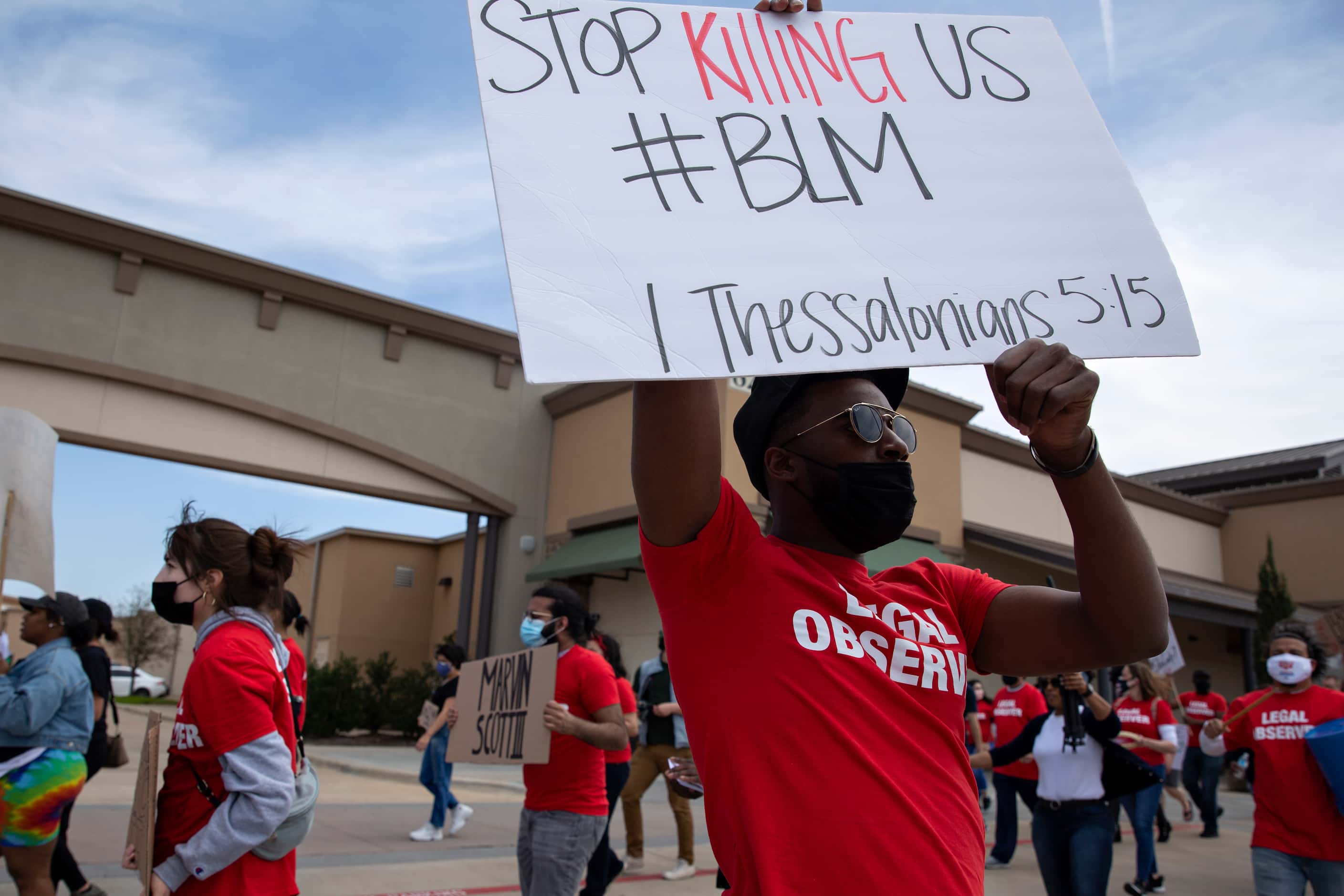 Zion Mayberry holds a sign as he participates in a march through the Allen Outlets on...