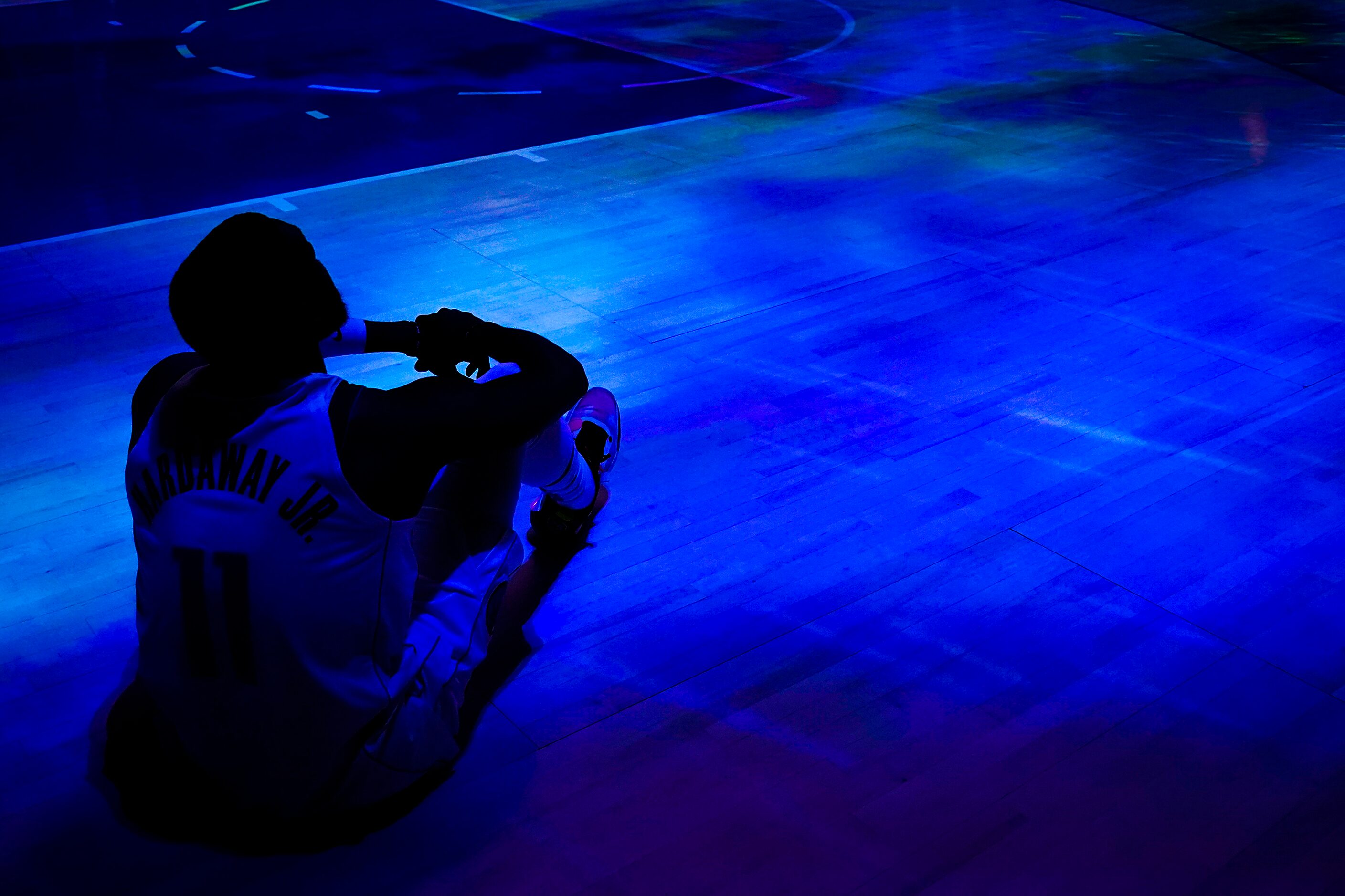 Dallas Mavericks guard Tim Hardaway Jr. sits on the court and watches a pregame video...