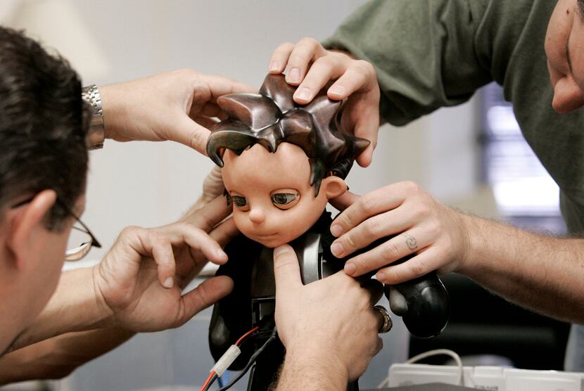 Jason Mitchell (left) and Joshua Varner make adjustments to Zeno, a robot boy creation by...