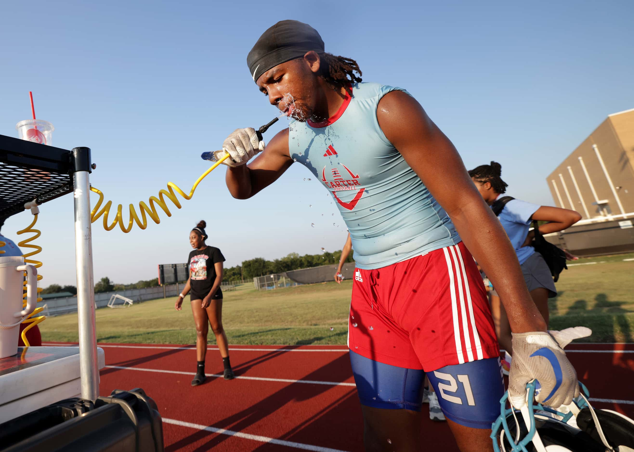 17-year-old Treveon Scott gets a drink as players attend their first day of football...