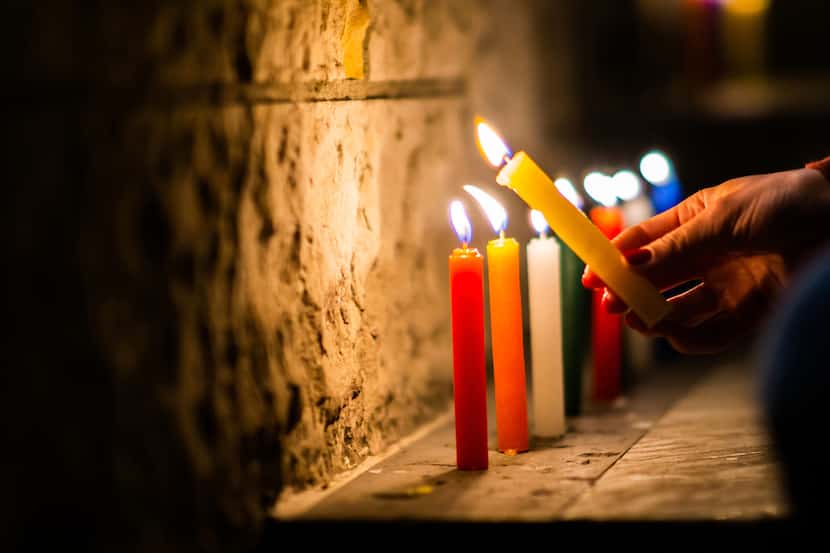 Una mujer enciende velas en Colombia para la celebración de la noche de velitas que se...