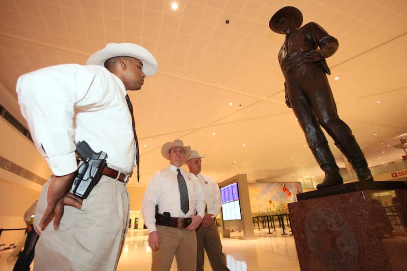 Texas Ranger David Armstrong, left, looks over the 'One Riot, One Ranger' statue at the main...