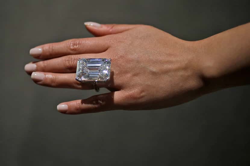 A Sotheby's employee models a 100-carat emerald-cut diamond, Friday, April 17, 2015, in New...