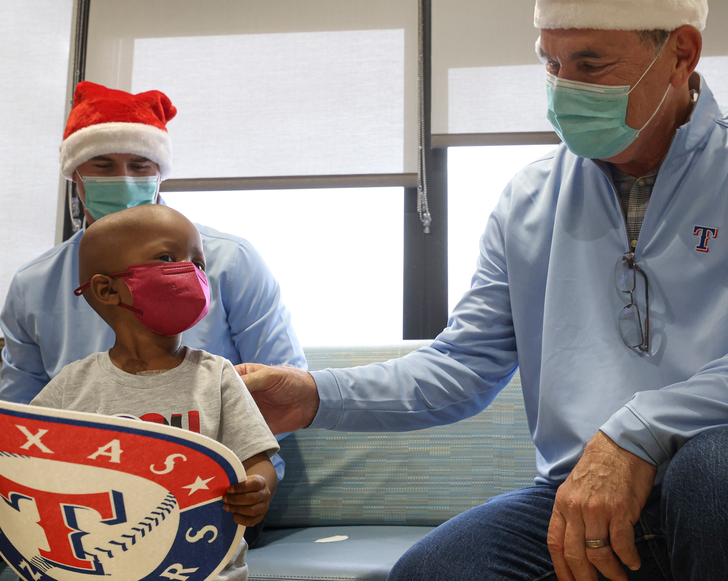 Texas Rangers pitcher John King, Isabella Foster, 2, and manager Bruce Bochy sit together at...